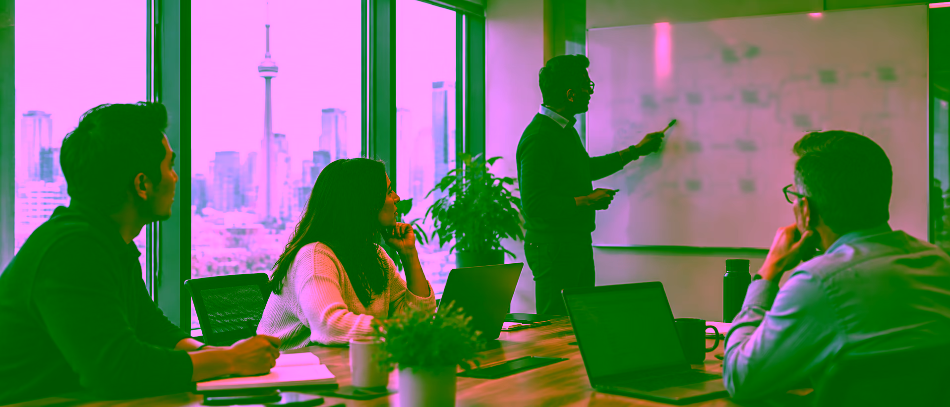 Consultants reviewing a plan on a whiteboard in a boardroom, with the Toronto skyline visible through the window